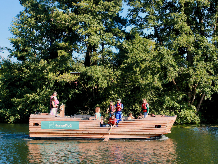Hansefloß auf der Wakenitz. Kinder in Rettungswesten spielen mit einem Kescher.